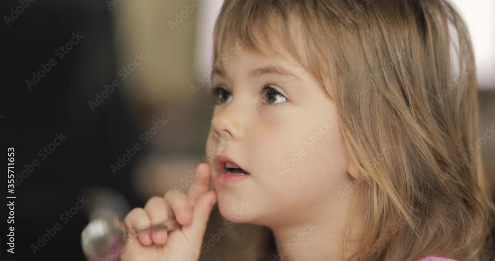 Adorable little girl in the sunlit living room watching tv and eating cereals Adorable little girl in the sunlit living room watching tv and eating cereals