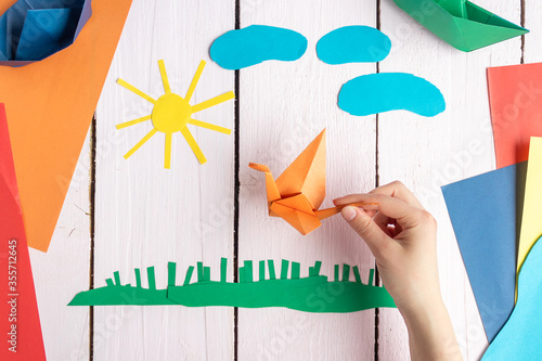 A girl plays with an origami toy that she made herself. Origami crane made of colored paper