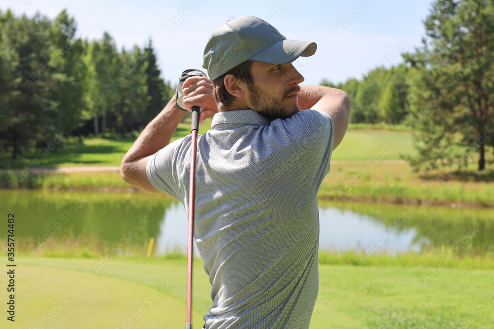 Golfer hits an fairway shot towards the club house. Golfer hits an fairway shot towards the club house.