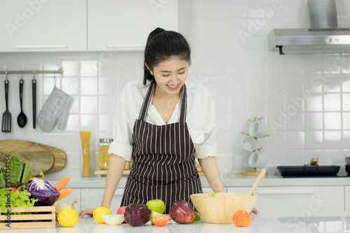 Asian young woman with glass of orange juice sitting at kitchen table Health food concept