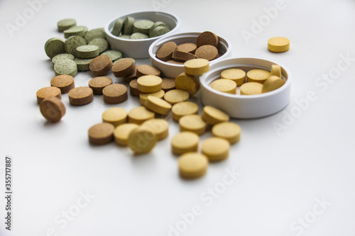 Supplements are scattered on the surface of the table close-up. White background. Vitamins and food additives help take care of health, have natural plant components and healthy nutrients.