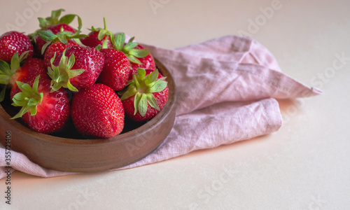 Fresh ripe delicious strawberries in a brown bowl on a light background. Copy space