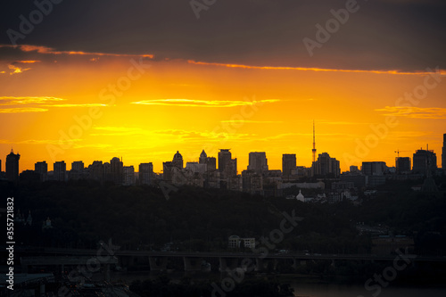 Beautiful sunset sky with clouds over city skyline background. Silhouette of Kyiv city. Ukraine.