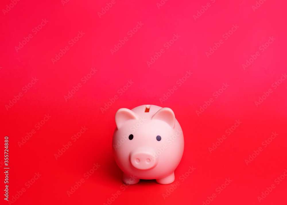 A Pink piggy bank isolated against red background 