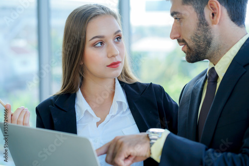two young caucasian business womwan and colleage discuss the financial business plan from laptop comuter in the office