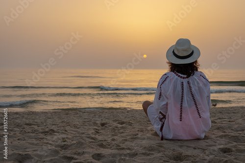 A girl enjoying the sunset sitting on the beach sand   in Portugal