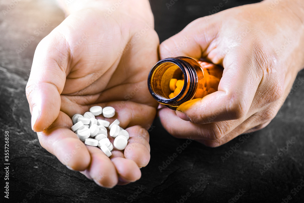 Hand holding on open palm with pill tablets medicine for healing. Man takes medicines with glass of water Hand holding on open palm with pill tablets medicine for healing. Man takes medicines with glass of water