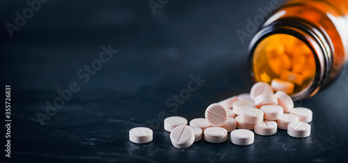 White medical pills or tablets with bottle on black background. Macro side view with copy space photo