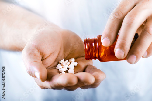Hand holding on open palm with pill tablets medicine for healing. Man takes medicines with glass of water