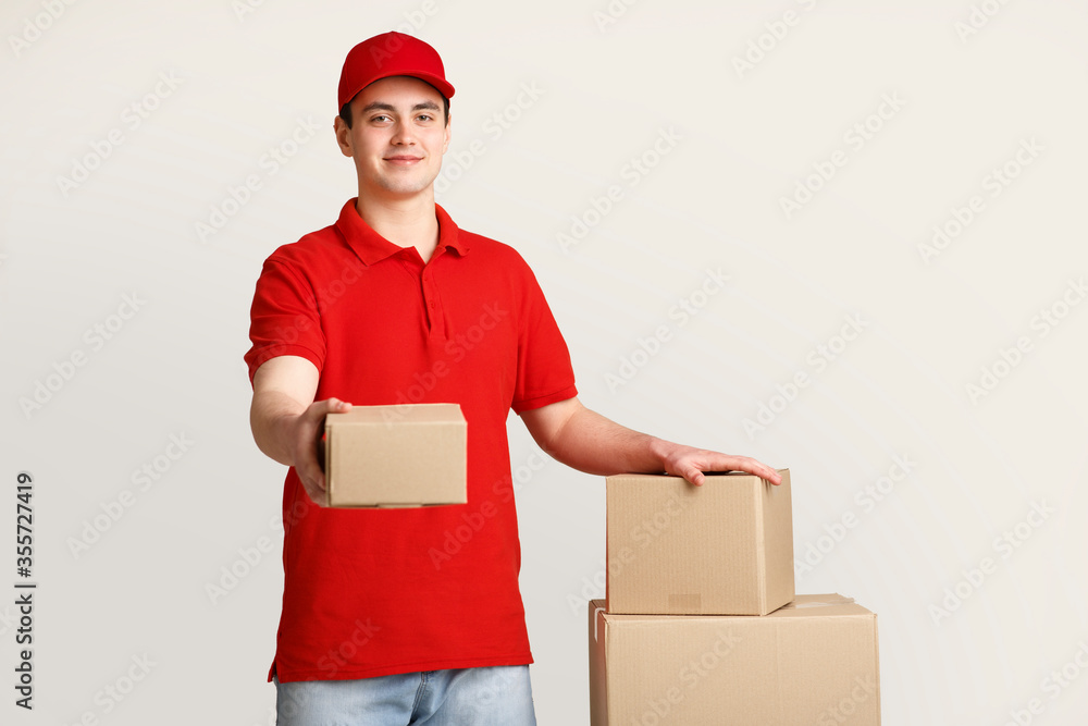 Issuance of parcels at post office. Courier holds out box and puts his hand on stack of parcels Issuance of parcels at post office. Courier holds out box and puts his hand on stack of parcels
