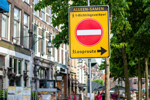 Social distancing in the city centre. One way trail sign during coronavirus outbreak, to alert people for one-way traffic, that says: "ALONE TOGETHER, one way traffic, walking route". 