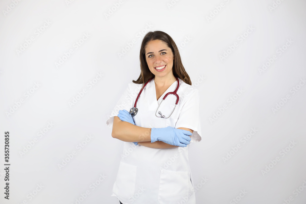 Young beautiful woman standing over white isolated background wearing her doctor uniform and smiling with arms crossed Young beautiful woman standing over white isolated background wearing her doctor uniform and smiling with arms crossed