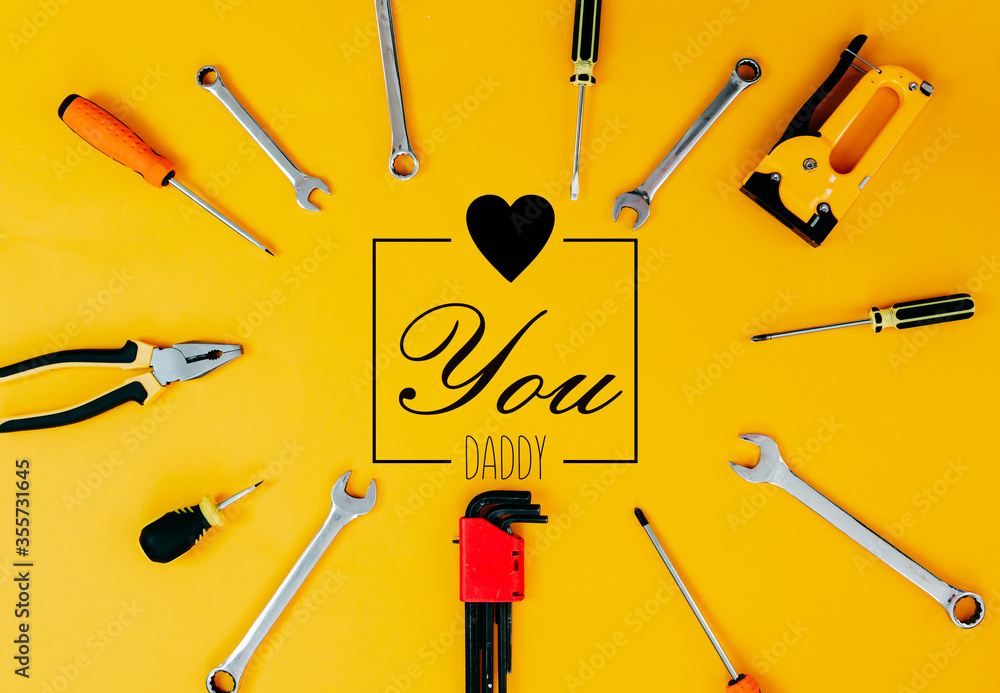 Tools top view on yellow background. Father's day card with tools. Plier, open wrenches, screwdrivers and staple gun in a cirlce.