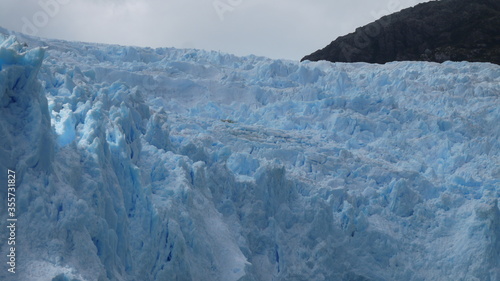 Panoramic views of a large glacier tongue on a blue lake with the high mountains of Canada in the background, and alpine scenery. We can see how the glacier has gone back in time