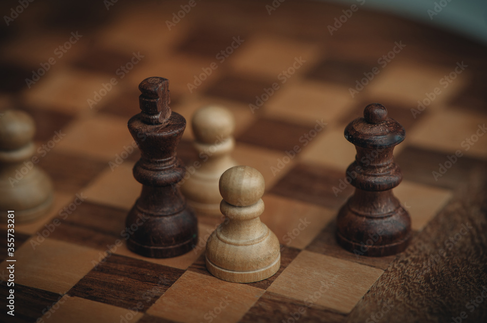 Chess board and chess pieces, Wooden chess pieces on a chess board. Close-up, pawn and queen, dark and light. Chess board and chess pieces, Wooden chess pieces on a chess board. Close-up, pawn and queen, dark and light.