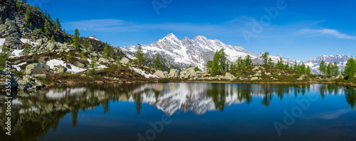 Alpine lake in idyllic environment amid rocks and forest. Natural reservoir of fresh water at high altitude on the mountains.