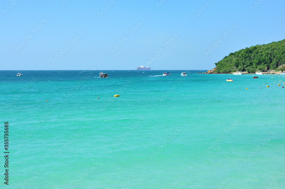 tropical beach with crystal clear turquoise water clear blue sky with boats in the water