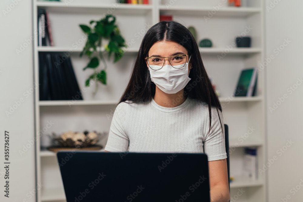 caucasian brunette girl with mask in the office, looks into the room with hopeful and happy eyes