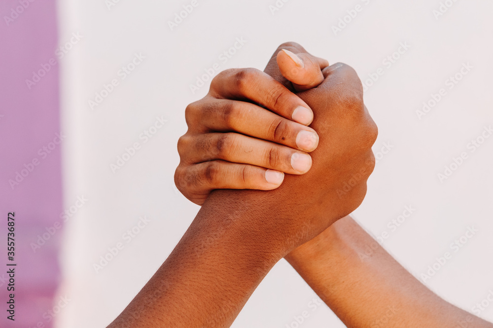 Black and white human hands in a modern handshake to show each other