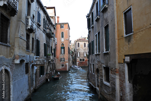 Venice channels with boats, gondolas, and colorful houses and towers © Sergey