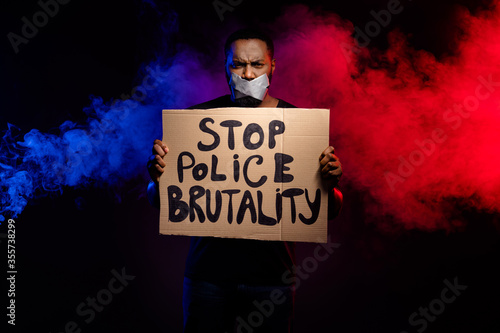 Photo of afro american guy hold paper card banner stop police brutality suffer speechless voiceless silence adhesive tape cover close lips isolated smoke black color background