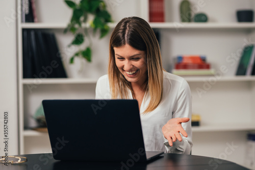 Head shot caucasian girl sitting at table  looking at laptop screen. woman reading message email with good news  chatting with clients online  working remotely. Webcam video call 