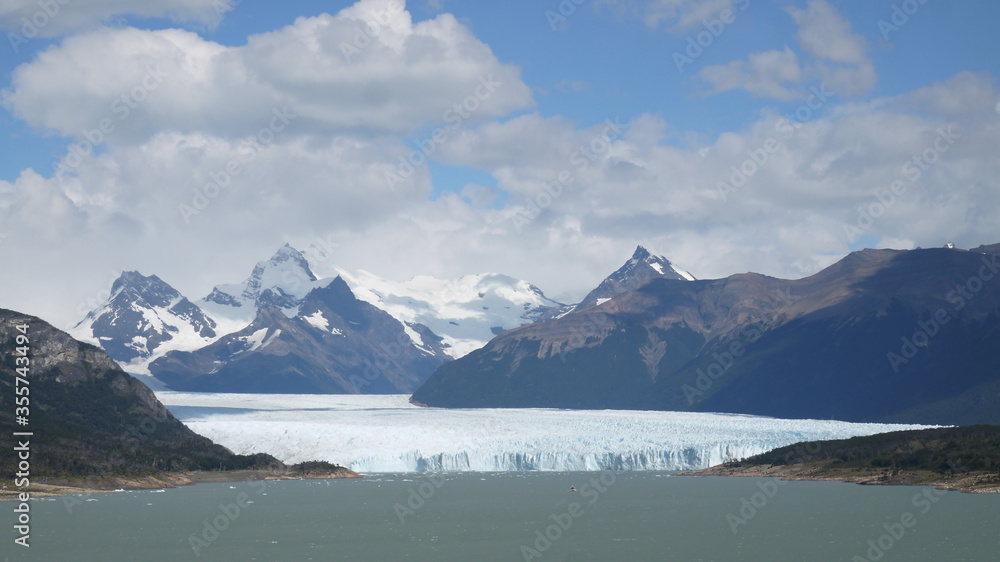 Panoramic views of a large glacier tongue on a blue lake with the high mountains of Canada in the background, and alpine scenery. We can see how the glacier has gone back in time