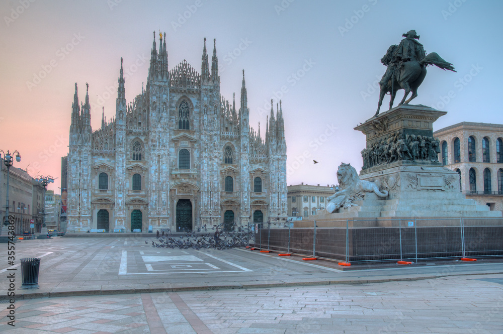 Sunrise scene of Duomo cathedral in Milano viewed behind statue of king Vittorio Emanuele II
