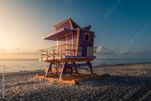 Lifeguard tower in early morning light. Fine sand shore in Miami Beach. Colorful sunrise