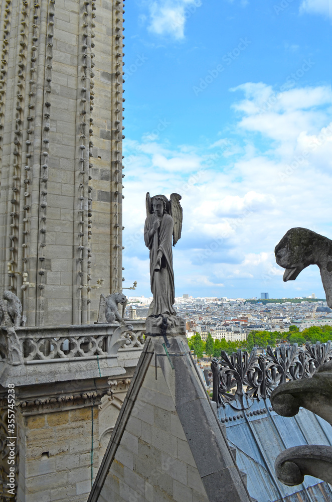 Angel blowing a trumpet and a gargoyle on the roof of the Notre Dame Cathedral in Paris, France