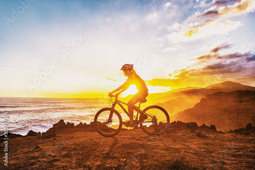 MTB mountain biking cyclist woman rider riding bike on summer coastal trail sunset landscape. Girl silhouette of athlete doing cycle sports outdoor. Healthy and Active lifestyle.