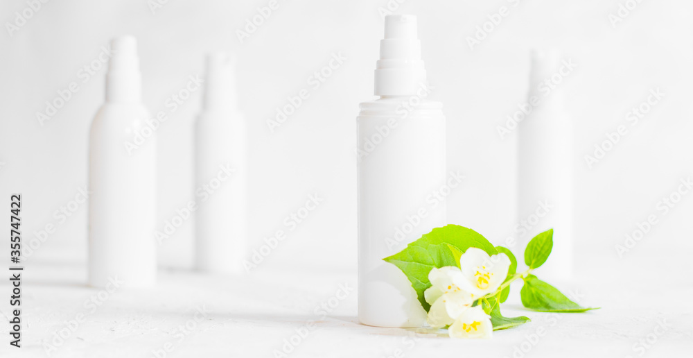 Unbranded skincare products plastic bottle with dispenser and flacons. Tube for cream shampoo. Green jasmine flowers and their shadows on the white background isolated. Mockup and copy space - obrazy, fototapety, plakaty 