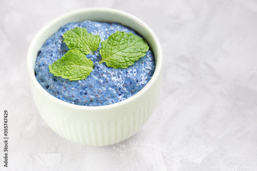 Blue spirulina or butterfly pea flower blue matcha powder chia seed pudding in porcelain bowl. Close up, top view, flat lay. Superfood and vegan food concept. Light gray background, copy space Blue spirulina or butterfly pea flower blue matcha powder chia seed pudding in porcelain bowl. Close up, top view, flat lay. Superfood and vegan food concept. Light gray background, copy space