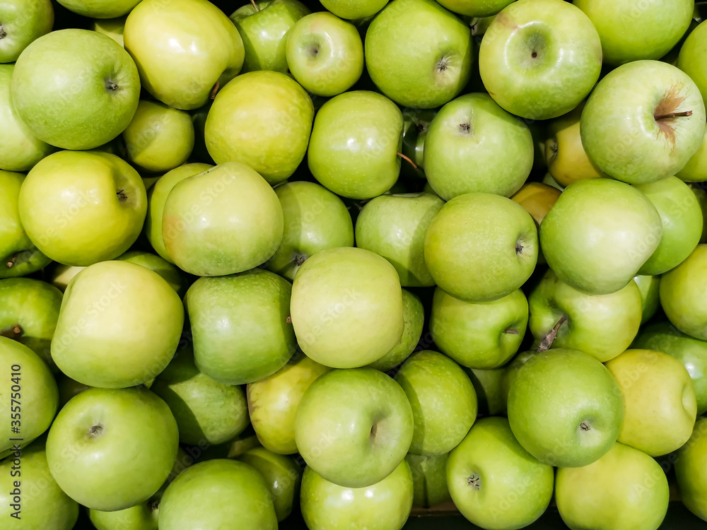 Solid background of green apples in a crate. Many organic Granny Smith apples. Healthy and affordable fruits in the supermarket, source of vitamin C. Pattern for design. View from above. Solid background of green apples in a crate. Many organic Granny Smith apples. Healthy and affordable fruits in the supermarket, source of vitamin C. Pattern for design. View from above.