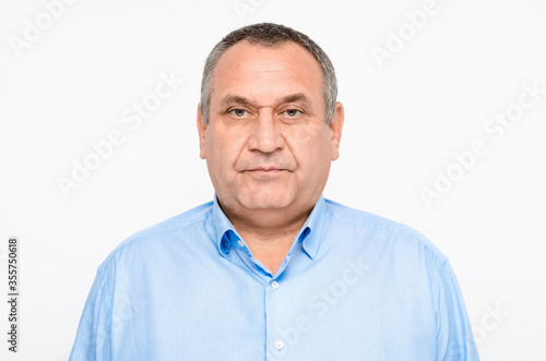 Portrait of an adult man with gray hair and eyebrows in a blue shirt on a white background. double chin. fat man. businessman