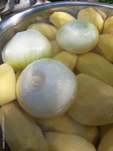 Peeled onions and potatoes in a metal bowl
