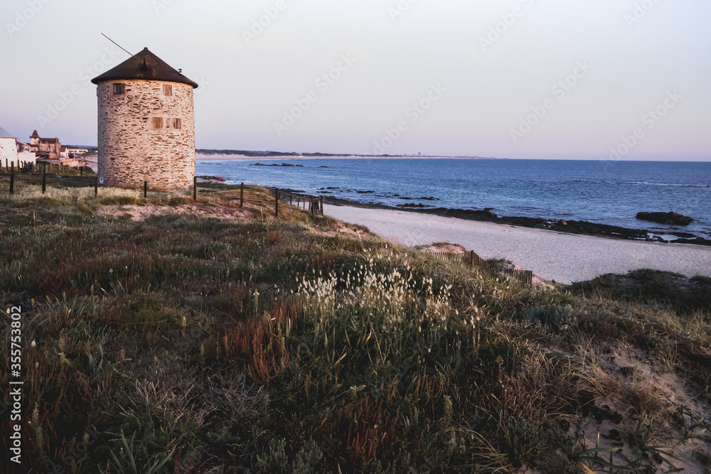 Stone windmill view, from a dune, on Apulia beach, Portugal.