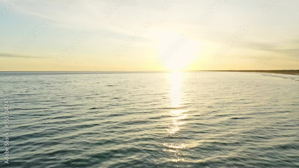 Aerial Shot of Sandy Shore, Calm Sea Waters and Bright Sun in the Background Aerial Shot of Sandy Shore, Calm Sea Waters and Bright Sun in the Background