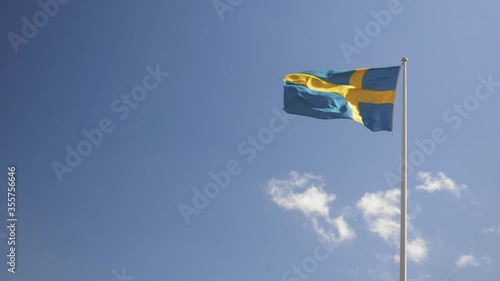 Swedish flag waving in the wind against a blue sky. Slow motion footage.