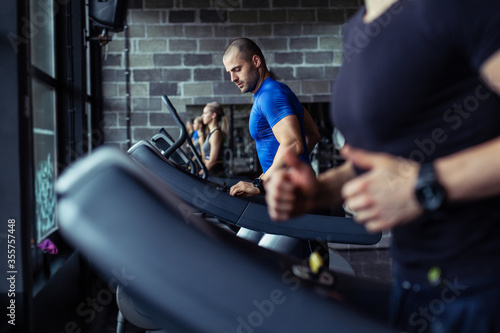 Young man in sportswear running on treadmill at gym.