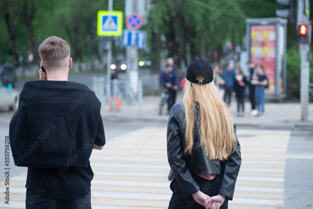 A girl and a young guy at a pedestrian crossing on a city street. A girl and a young guy at a pedestrian crossing on a city street.