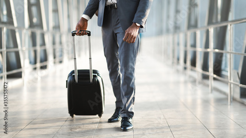 Unrecognizable Business Guy Walking With Suitcase In Airport Terminal
