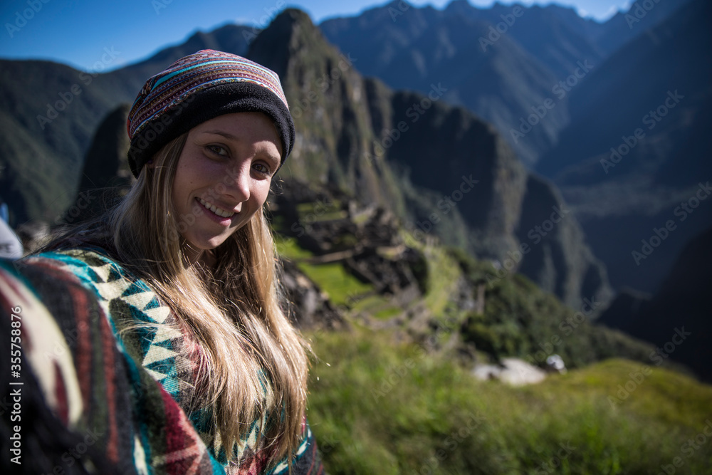 Blonde young woman smiling at the camera in machu picchu in a selfie