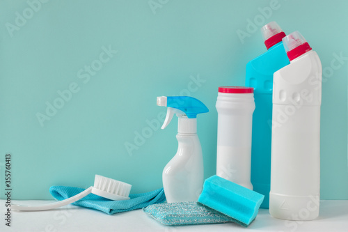 Four white bottles of household chemicals on a blue background with copy space.