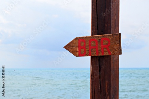 wooden sign indicating a beach bar with the sea in the background