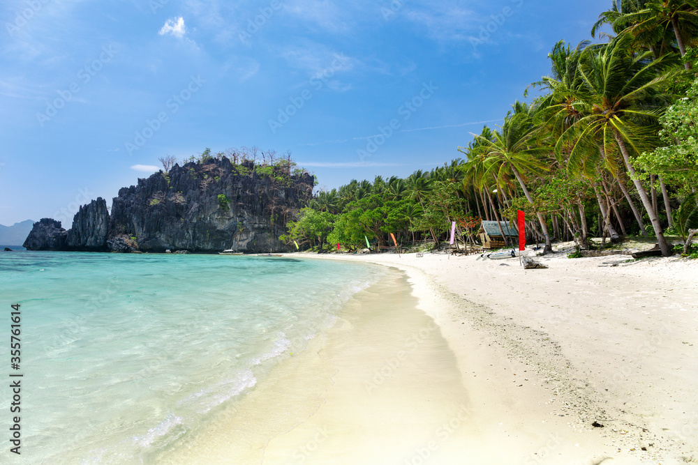 Tropical beach with bungalows and colored flags. White sand and crystal clear blue water.