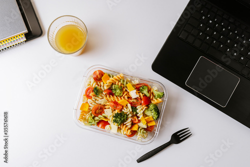 Healthy food in lunch box, on working table with laptop