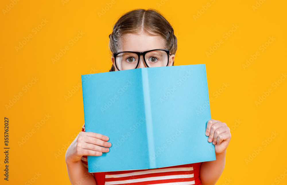 Schoolgirl hiding face behind textbook. Schoolgirl hiding face behind textbook.