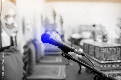 Black and white image. Microphone with blurry indoor location for Buddhist activities. The concept of speaker.