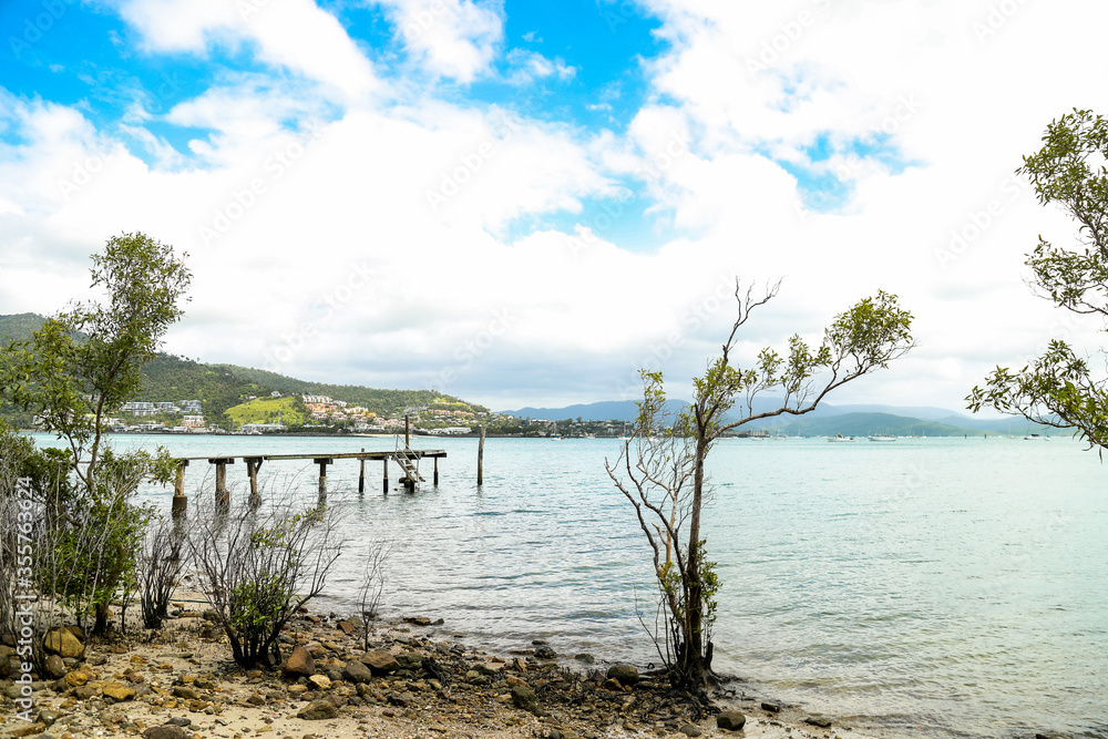 Afternoon view of small rustic wooden jetty at Mandalay off Airlie Beach when the tide is out